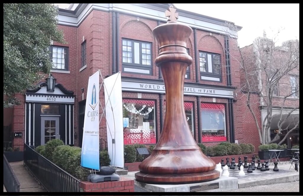 Giant 20 foot tall chess king piece standing next to people for scale